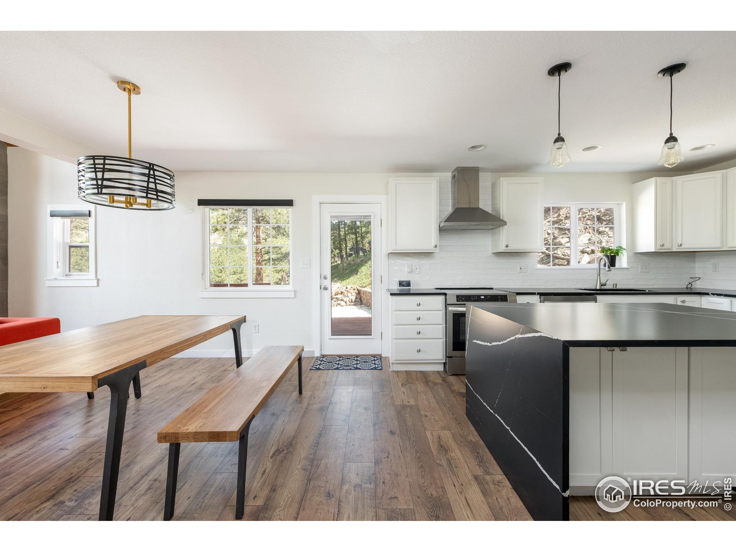 93 Pine Needle Road Boulder, CO 80304 - Photo 37 of 48 a kitchen with stainless steel appliances kitchen island granite countertop a table chairs in it and wooden floors