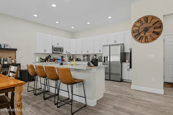 a kitchen with stainless steel appliances granite countertop a dining table chairs refrigerator and sink