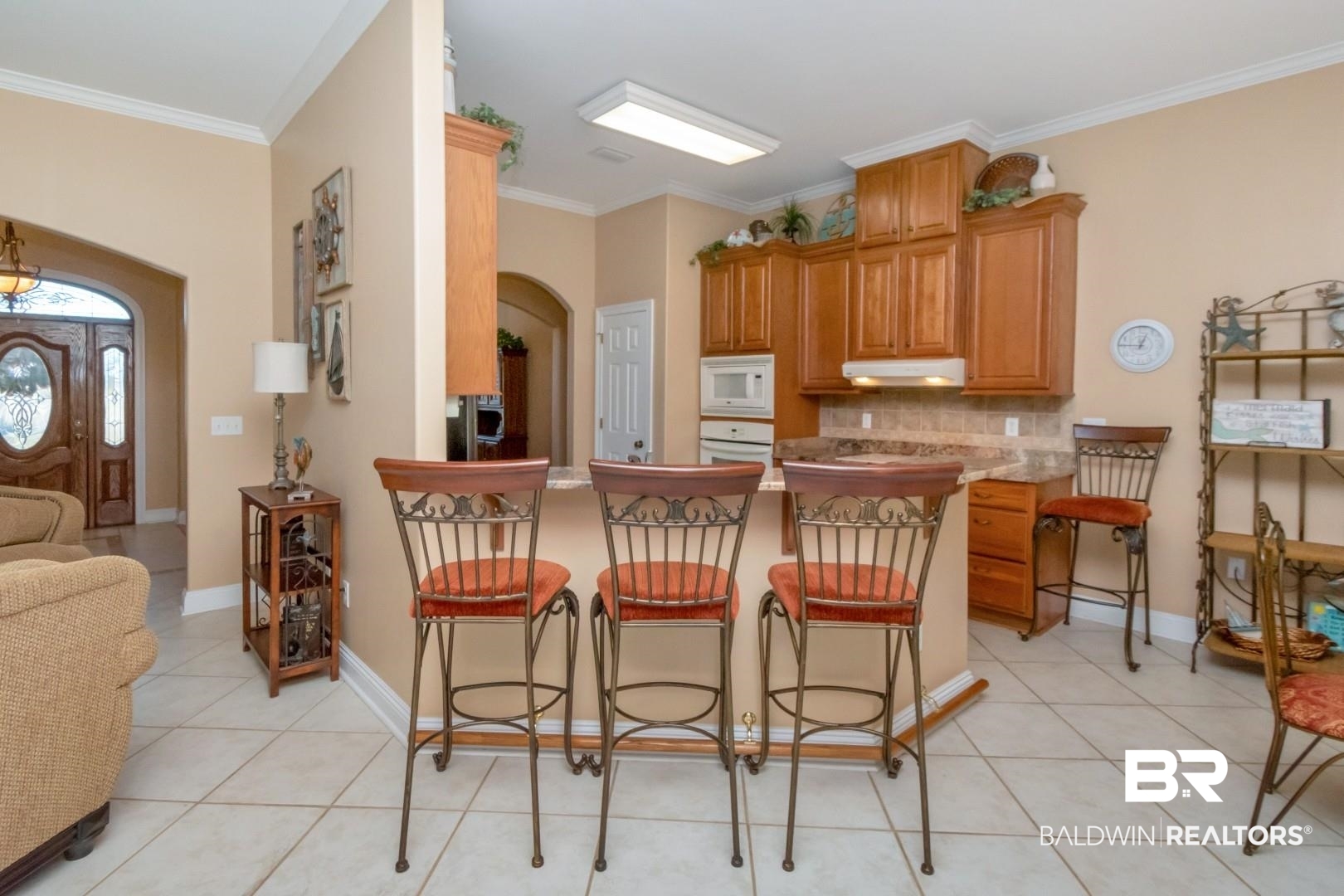 9905 Carnoustie Court Foley, AL 36535 - Photo 10 of 31 Kitchen with a peninsula, a kitchen bar, arched walkways, brown cabinets, and light tile patterned floors