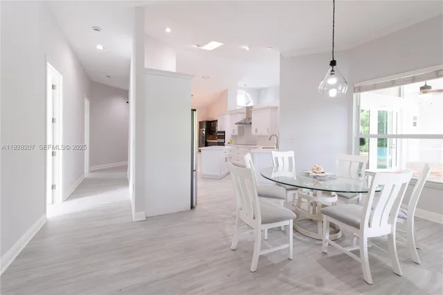 a view of a dining room and livingroom with furniture wooden floor kitchen view