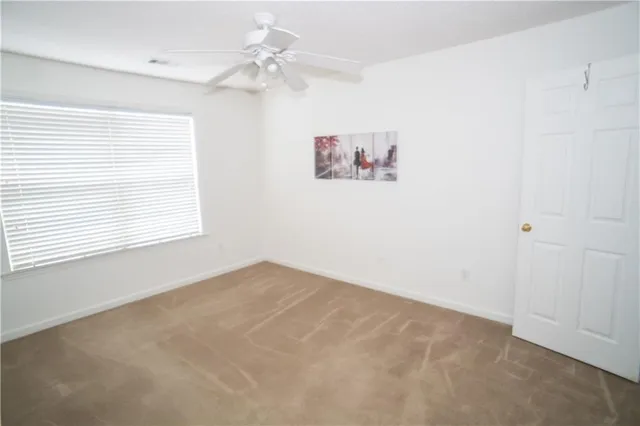 an empty room with windows and fan