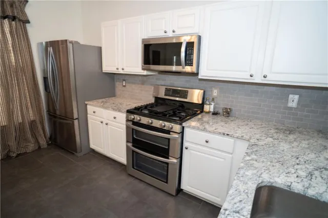 a kitchen with stainless steel appliances white cabinets white stove a microwave and a refrigerator