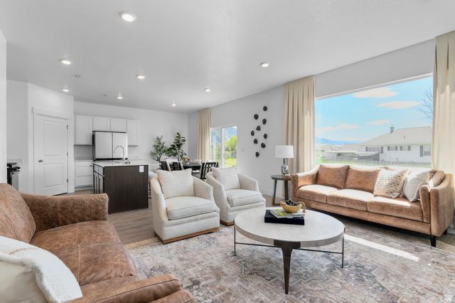 2819 South 710th West, Unit 14 Logan, UT 84321 - Photo 11 of 24 Bright, open-concept living area featuring a large picture window, recessed lighting, wood-finish flooring, a kitchen island with seating, and stainless steel appliances