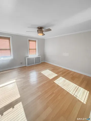 a view of empty room with wooden floor and fan
