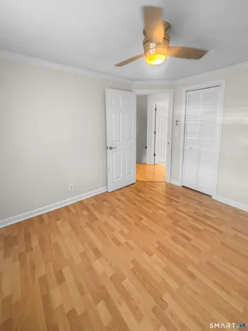 an empty room with wooden floor and a ceiling fan