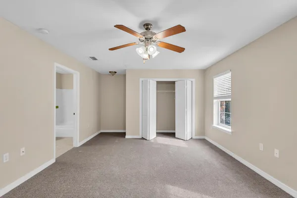 a view of an empty room with window and a ceiling fan