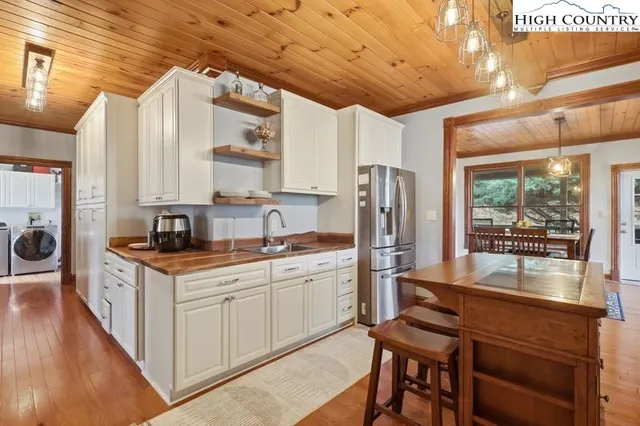 a kitchen with stainless steel appliances granite countertop a stove a sink dishwasher a refrigerator white cabinets and wooden floor