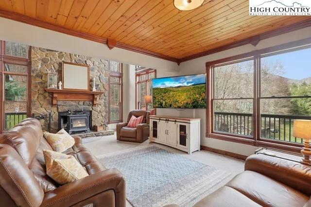 a living room with furniture a flat screen tv and a floor to ceiling window