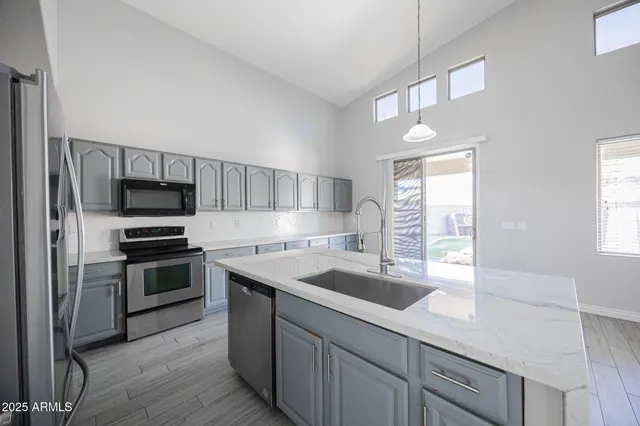 an empty room with windows and chandelier fan