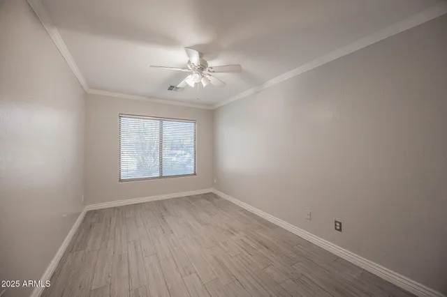 an empty room with wooden floor and a ceiling fan