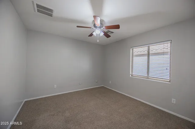 an empty room with chandelier fan and windows
