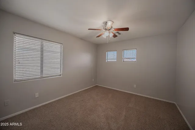 an empty room with a chandelier fan and windows