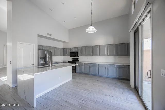 a large kitchen with a large counter top a sink stainless steel appliances and cabinets