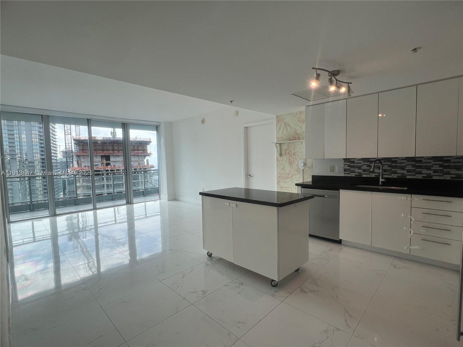 92 Southwest 3rd Street, Unit 3803 Miami, FL 33130 - Photo 6 of 27 a large kitchen with kitchen island a large counter top space a stove and a large window