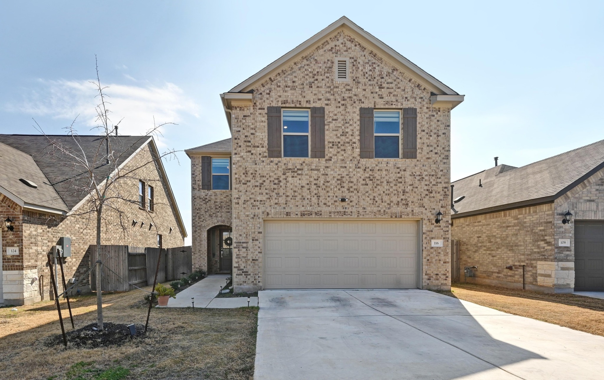 View of front of home with brick siding, driveway, and a garage