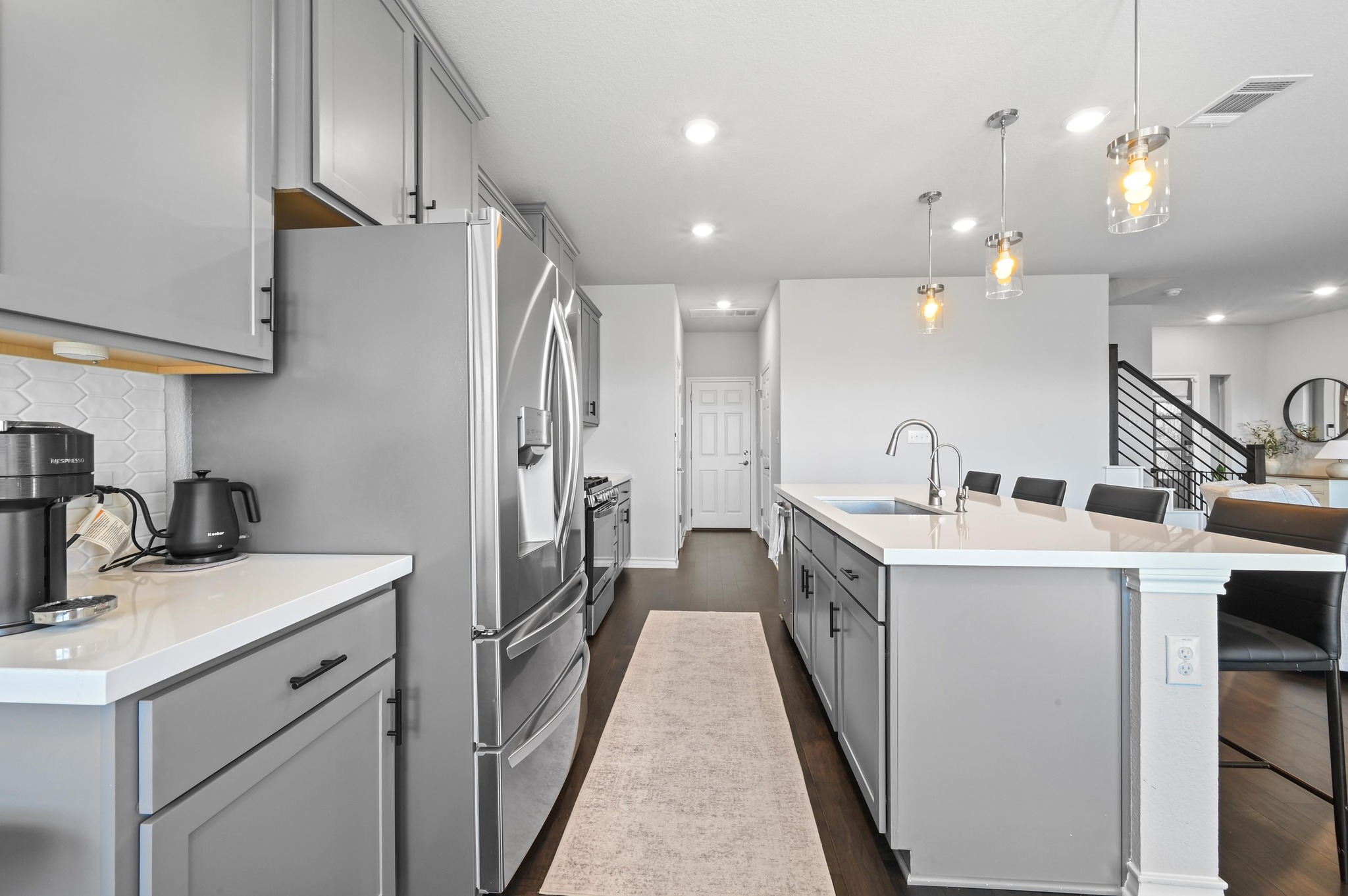 116 Small Seed Drive Buda, TX 78610 - Photo 12 of 40 Kitchen featuring gray cabinets, a kitchen breakfast bar, stainless steel appliances, dark wood-style floors, and hanging light fixtures