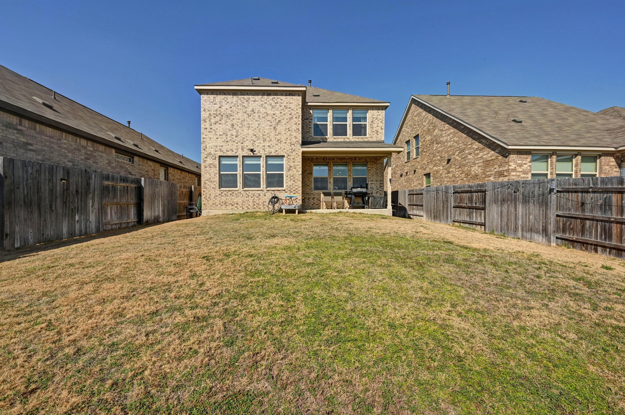 116 Small Seed Drive Buda, TX 78610 - Photo 26 of 40 Back of property with brick siding, a patio, and a fenced backyard