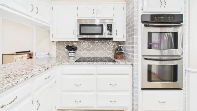 a kitchen with granite countertop white cabinets and stainless steel appliances