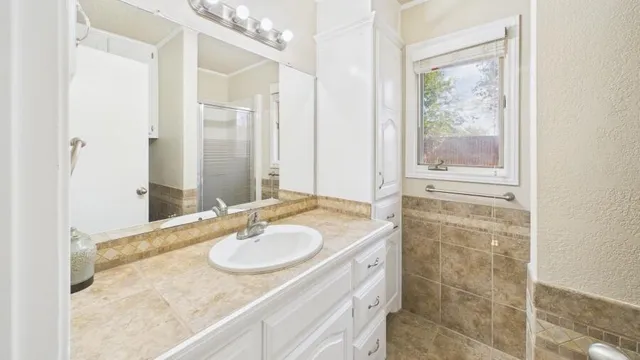 a bathroom with a granite countertop sink a mirror and a shower