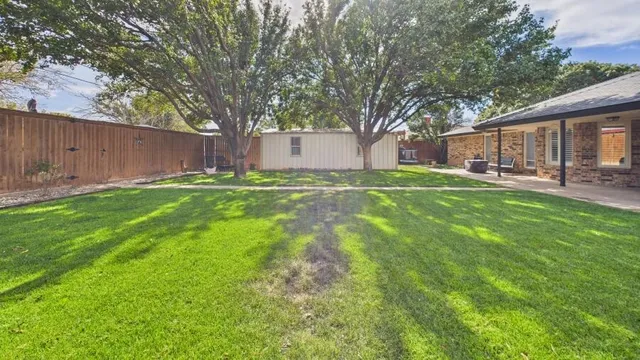 a patio with table and chairs and a big yard