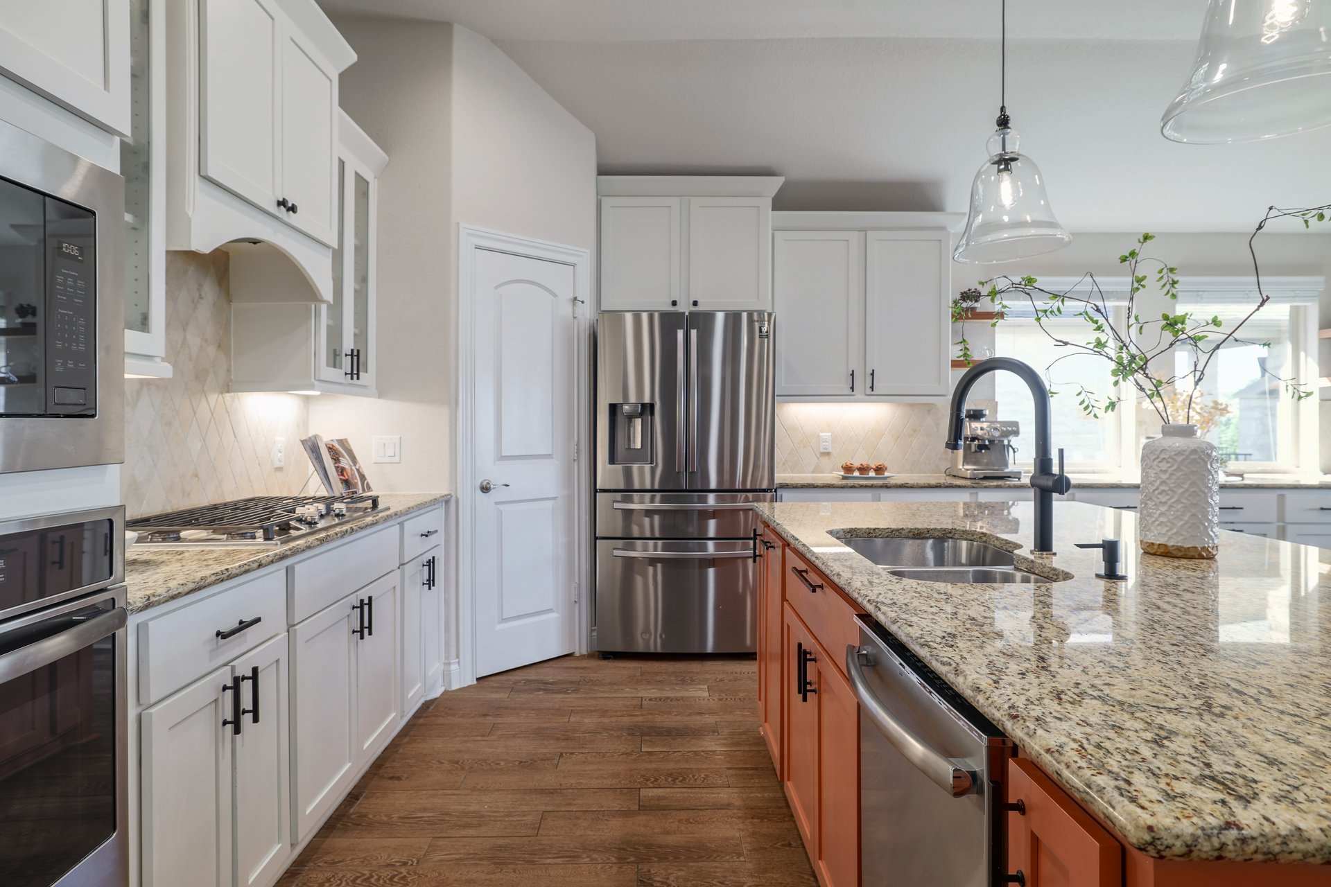 173 Santa Maria Street Georgetown, TX 78628 - Photo 17 of 39 Gourmet kitchen featuring granite countertops, stainless steel appliances, white cabinetry with matte black hardware, wood-finish flooring, and a large island with sink