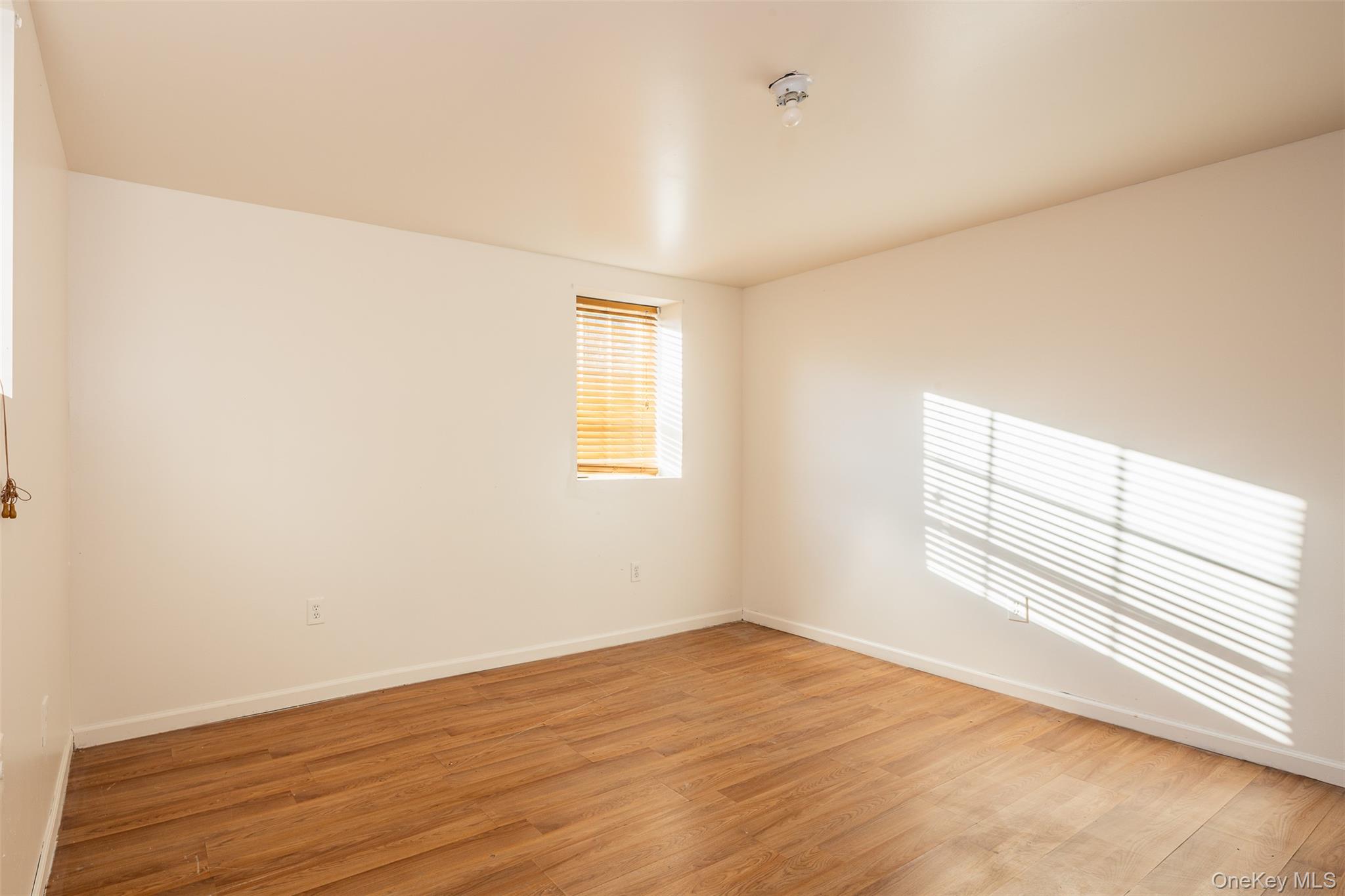 182 Whittier Drive Mastic Beach, NY 11951 - Photo 18 of 25 an empty room with wooden floor and windows