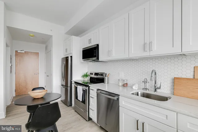 a kitchen with stainless steel appliances white cabinets sink and stove