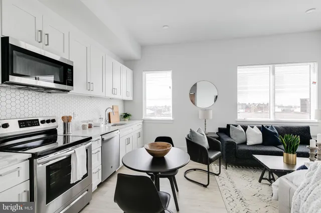 a open kitchen with stainless steel appliances granite countertop a stove a sink dishwasher a microwave oven with white cabinets and wooden floor