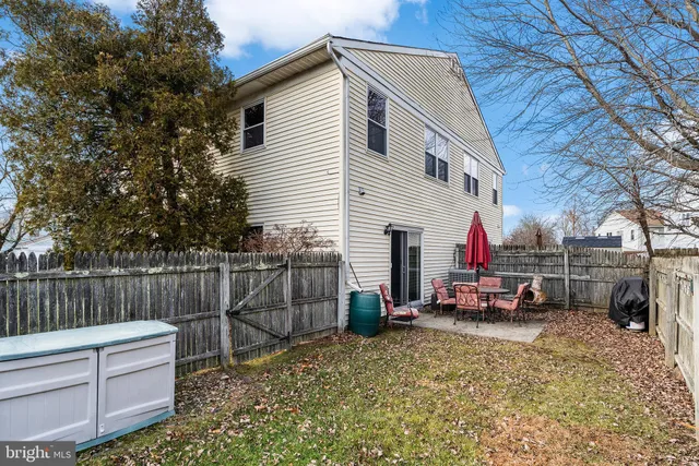 a view of a white house with a small yard and wooden fence