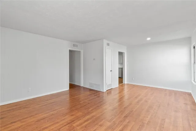 a view of an empty room with wooden floor and closet