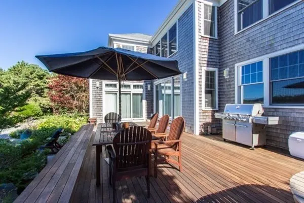 a view of a roof deck with table and chairs under an umbrella with wooden floor