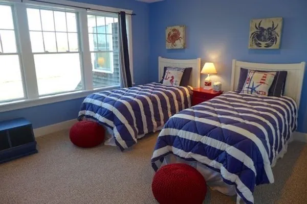 a bedroom with two beds and next to a window