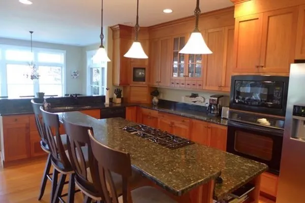 a kitchen with stainless steel appliances granite countertop a stove a refrigerator a kitchen island a dining table and chairs