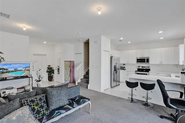 a living room with furniture and a dining table with kitchen appliances