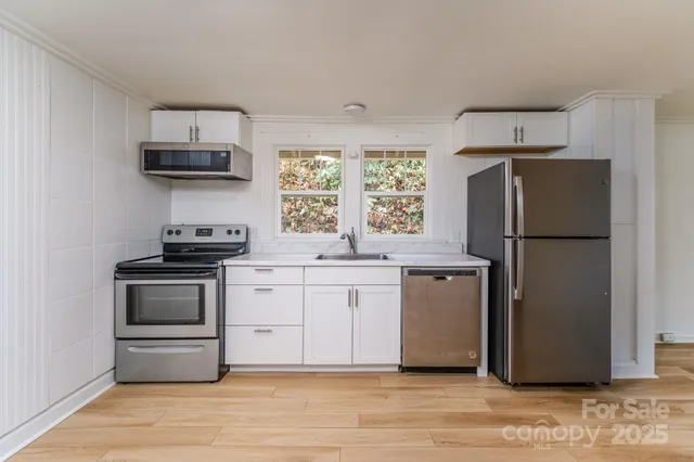 a kitchen with stainless steel appliances cabinets and wooden floor