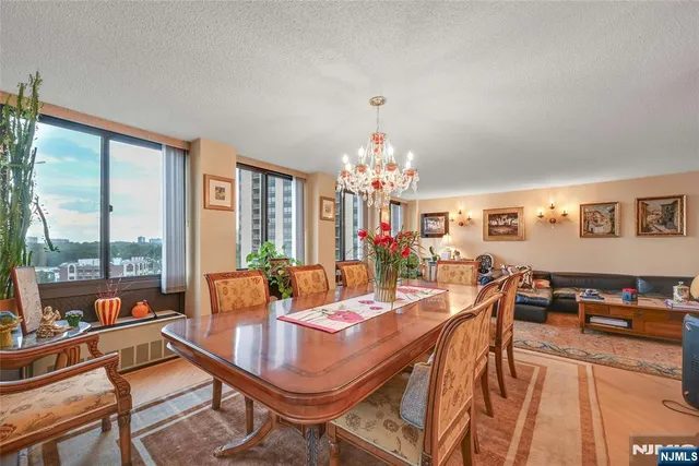 a view of a dining room with furniture a chandelier and large windows