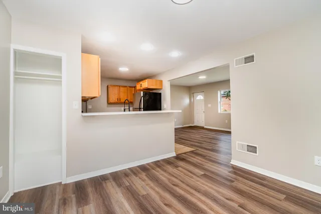 a view of a hallway with wooden floor and a kitchen space