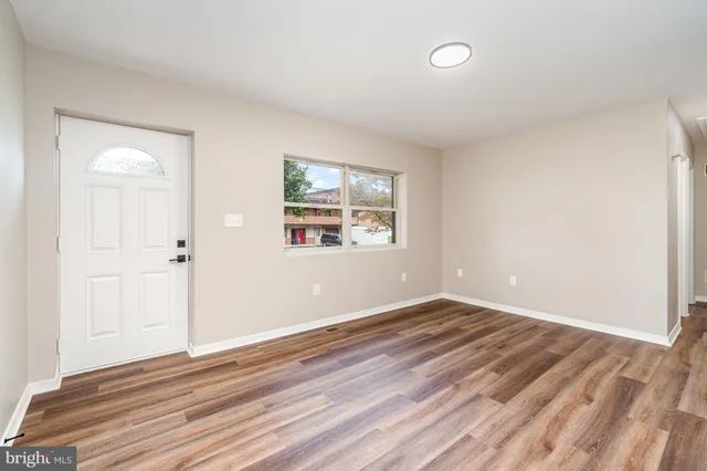 an empty room with wooden floor and windows
