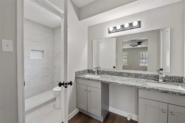 a bathroom with a granite countertop sink a large mirror a bathtub and shower