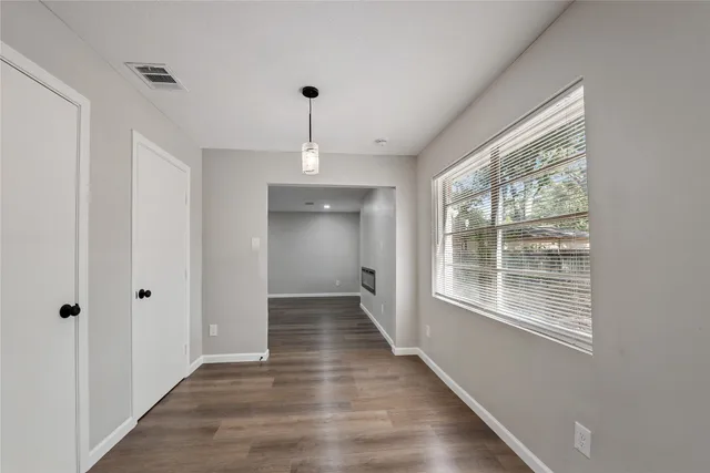 a view of an empty room with wooden floor and a window