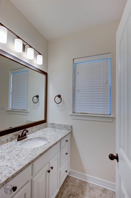 922 Antler Drive Haughton, LA 71037 - Photo 18 of 24 White vanity with an integrated sink, speckled countertop, bronze-finish faucet, and a large framed mirror