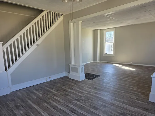a view of an empty room with wooden floor and fan