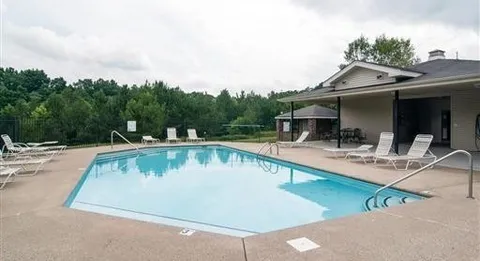 a view of swimming pool with outdoor seating and house in the background