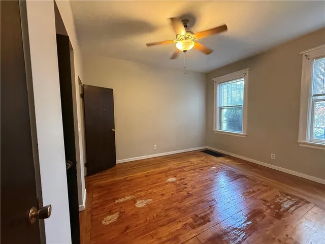 a view of an empty room with window and wooden floor