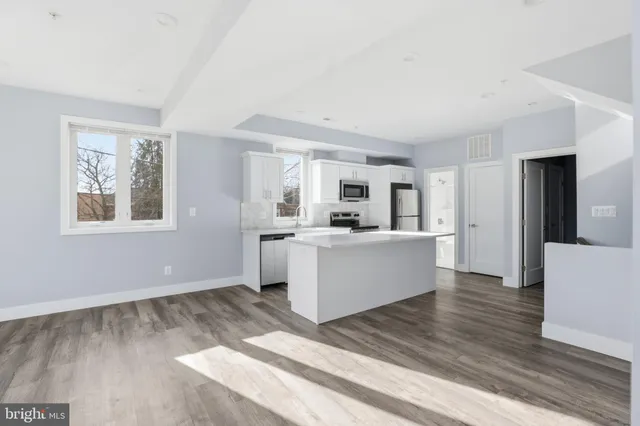 a view of an empty room with wooden floor and stairs