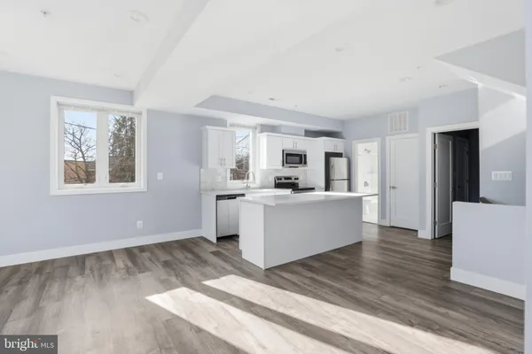 a view of an empty room with wooden floor and stairs
