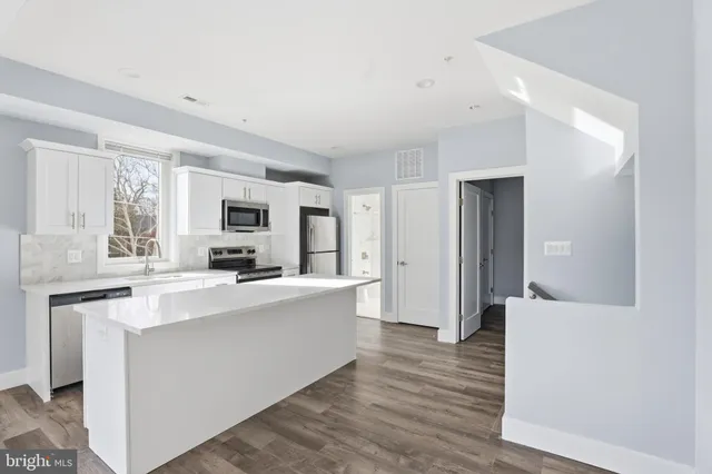 a large white kitchen with sink and refrigerator