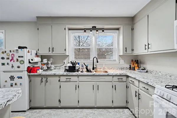 a kitchen with kitchen island granite countertop a sink cabinets and window