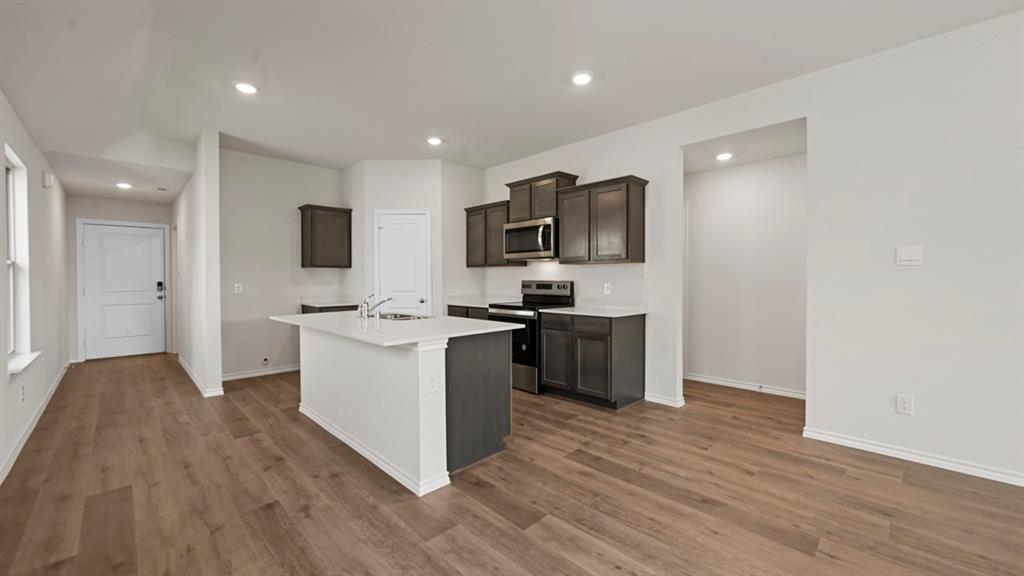 1663 Blaire Drive Tyler, TX 75704 - Photo 13 of 26 Open-concept living space featuring wood-finish flooring, recessed lighting, and a kitchen island with a white countertop and dark base cabinetry