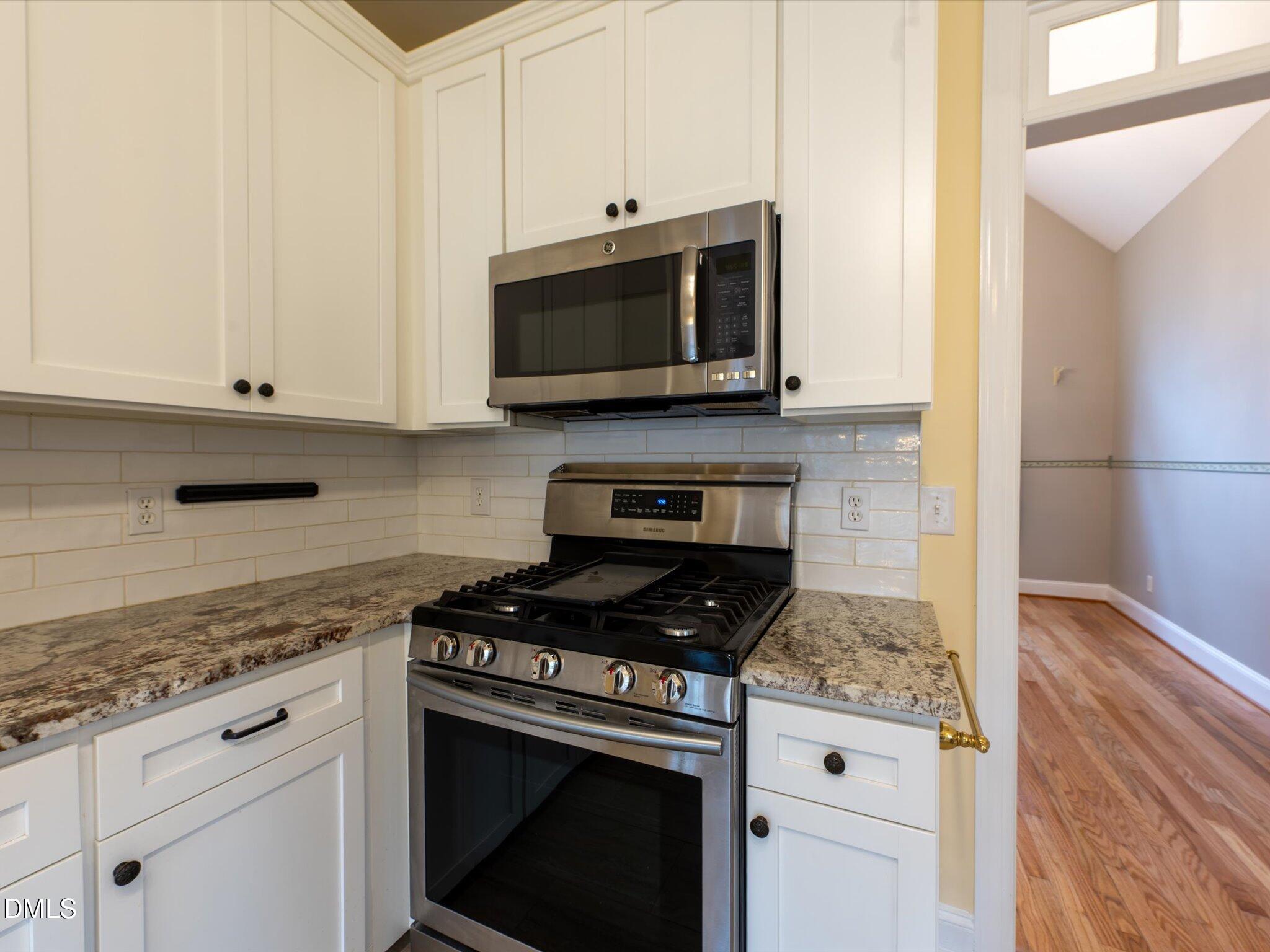 6832 Cool Pond Road Raleigh, NC 27613 - Photo 9 of 27 a kitchen with stainless steel appliances granite countertop white cabinets and a stove a oven with white countertops